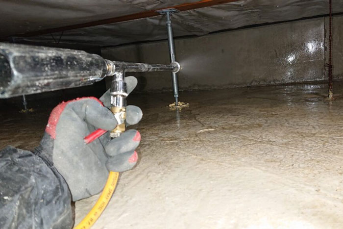 駆除対策屋アシストの施工写真：床下の土壌側に薬剤を散布する作業